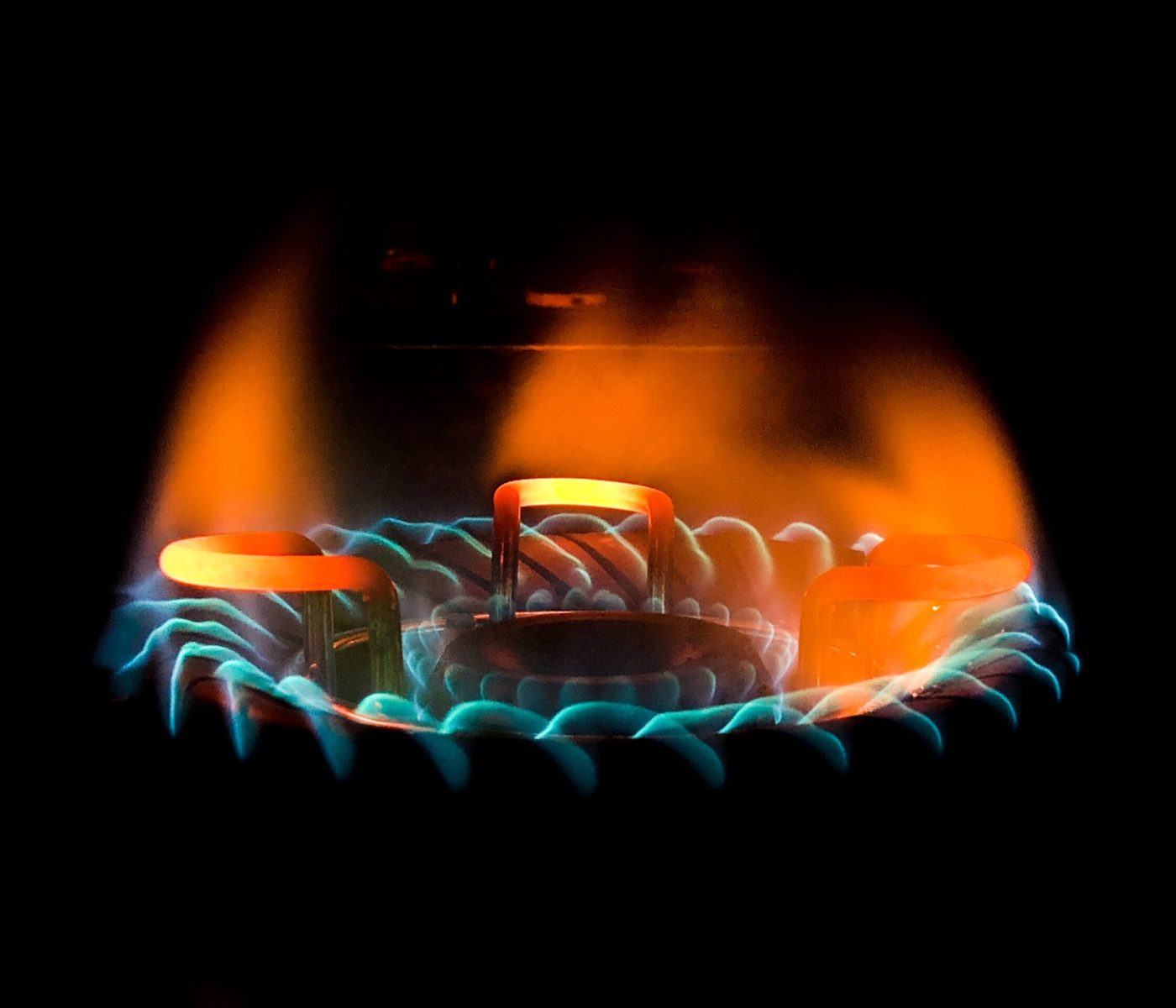 A closeup shot of a beautiful blue-green flame in a gas stove